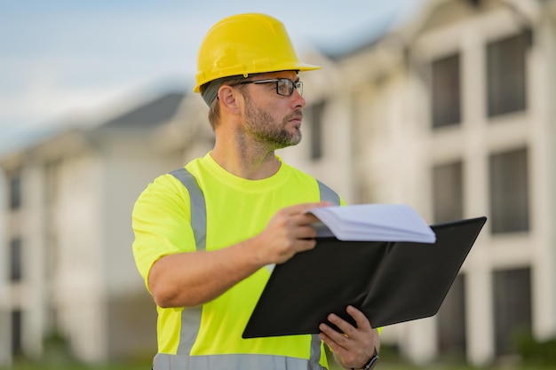 Engenheiro com prancheta construtor de inspeção de construção no local trabalhador de construção com capacete