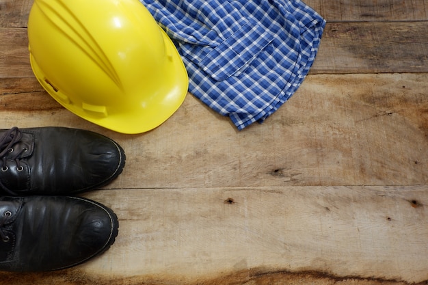 Engenheiro conjunto com sapatos de segurança, capacete, camisa em fundo de madeira