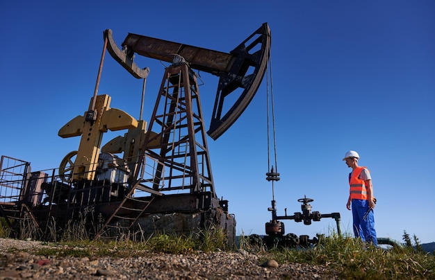 Foto engenheiro controlando a operação de uma plataforma de petróleo sob o céu azul