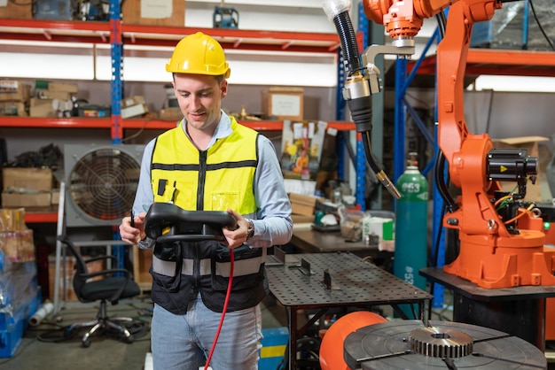 Engenheiro de automação masculino testando nova máquina de solda de braço robótico usando laptop operando na fábrica