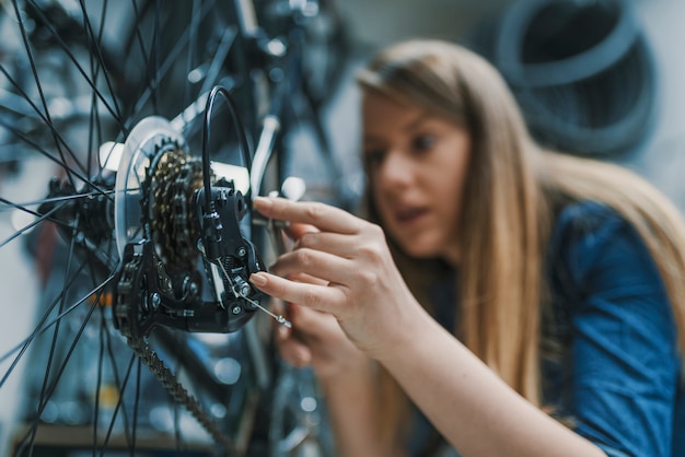 engenheiro de bicicleta de mulher está consertando uma bicicleta na oficina