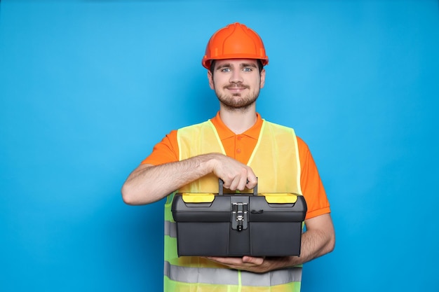 Engenheiro de capacete com mala de ferramentas em fundo azul