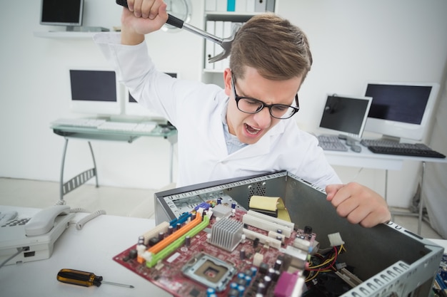 Engenheiro de computador segurando martelo sobre console quebrado