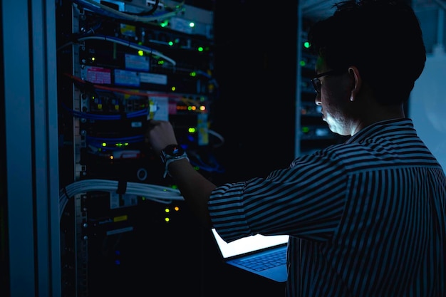 Engenheiro de computadores está a instalar uma rede na sala de servidores Técnico de Manutenção de Sistemas Engenheiro masculino a trabalhar na sala de servos num centro de dados moderno