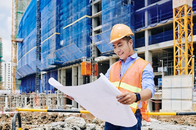 Engenheiro de construção examinando planta de construção