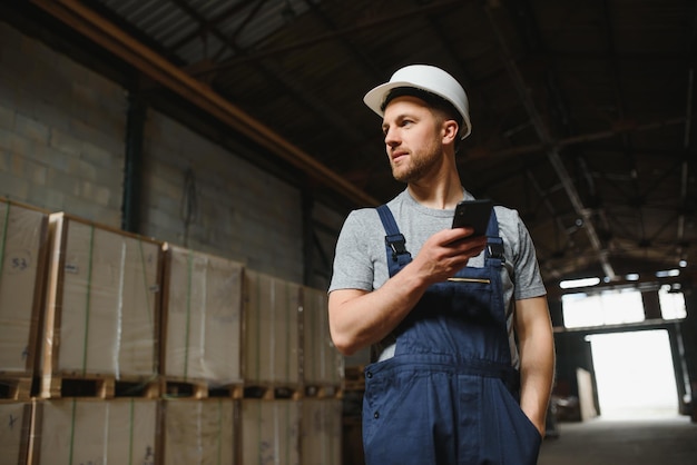 Engenheiro de equipe de gerenciamento ou capataz em pé verificando informações de trabalho sobre gerenciamento de produção industrial dentro da fábrica por telefone Conceito de trabalho em equipe