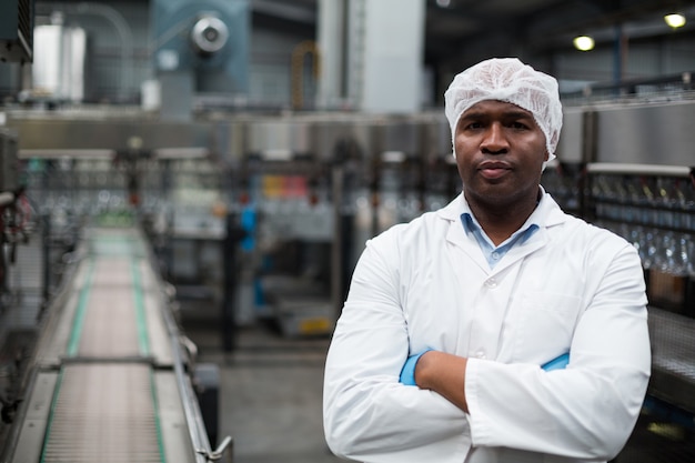 Engenheiro de fábrica em pé com os braços cruzados na fábrica de garrafas