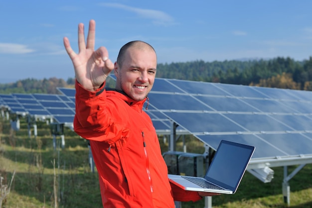 engenheiro de homem de negócios usando laptop em painéis solares planta campo de energia ecológica em segundo plano