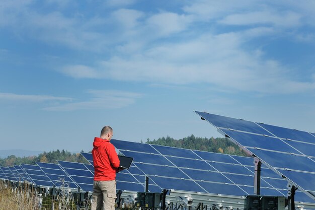 engenheiro de homem de negócios usando laptop em painéis solares planta campo de energia ecológica em segundo plano