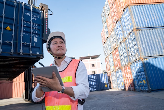 Foto engenheiro de logística controle no porto, carregando contêineres para caminhões exportando e importando logística