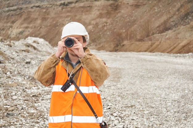 Engenheiro de mineração ou rodoviário usando uma luneta contra o fundo de uma mina