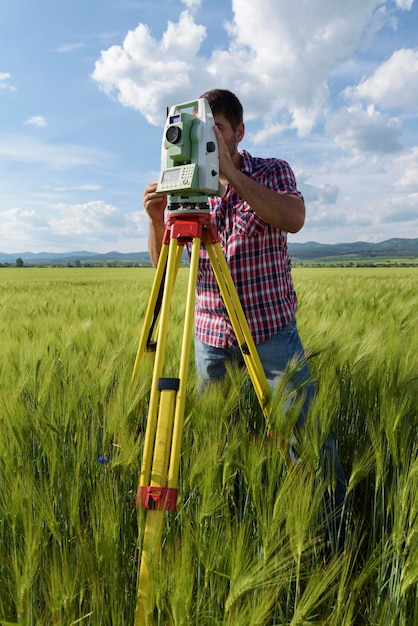 Foto engenheiro de pé com equipamento no campo contra o céu