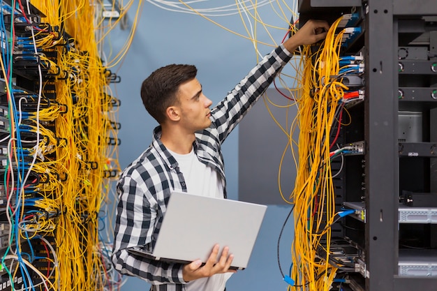 Engenheiro de rede na sala do servidor com um laptop tiro médio