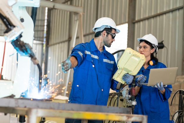 Engenheiro de robótica trabalhando na manutenção do braço robótico moderno no armazém da fábrica