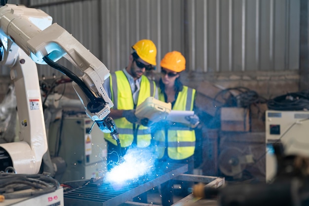 Engenheiro de robótica trabalhando na manutenção do braço robótico moderno no armazém da fábrica