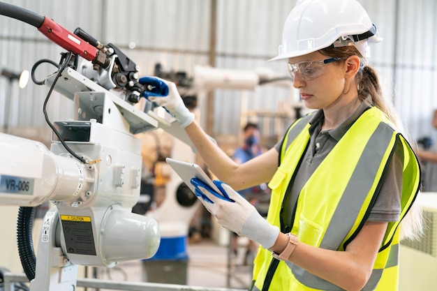 Engenheiro de robótica trabalhando na manutenção do braço robótico moderno no armazém da fábrica