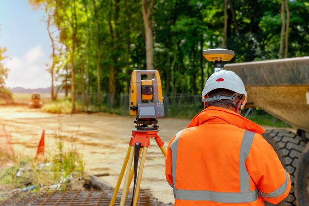 Foto engenheiro de site surveyor com estação de posicionamento total no canteiro de obras de construção de novas estradas