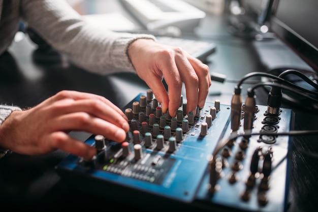 Engenheiro de som masculino mãos no painel de controle de volume. estúdio de gravação digital de música.