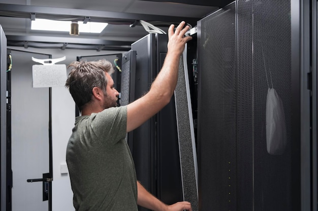 Engenheiro de TI trabalhando na sala de servidores ou data center. O técnico coloca em um rack um novo servidor de supercomputador de mainframe de negócios corporativos ou fazenda de mineração de criptomoedas.