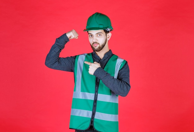 Foto engenheiro de uniforme verde e capacete demonstrando seu punho.