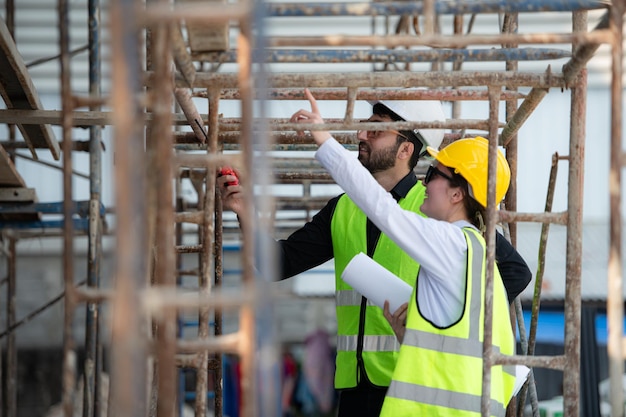 Engenheiro e arquiteto trabalhando no canteiro de obras, verificando planos e processos