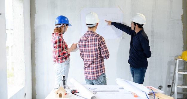 Engenheiro e arquitetos trabalhando e discutindo no canteiro de obras. Inspeção do proprietário no projeto da vila e na construção da propriedade.