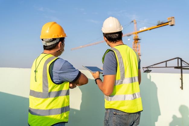 Engenheiro e capataz inspecionam o guindaste no canteiro de obras.