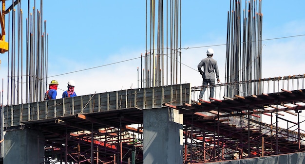 Foto engenheiro e trabalhadores no canteiro de obras de alto padrão e textura de aço e cimento e céu azul.