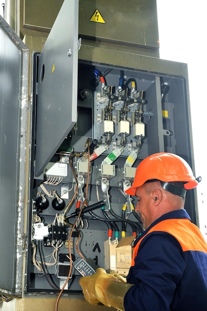 Engenheiro eletricista mede a tensão em um gabinete de controle elétrico.