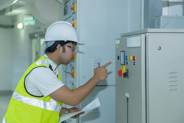 Engenheiro elétrico asiático, homem bonito, verifica a carga no comutador de média tensãoBay control unitThailand people