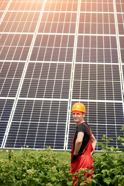 Engenheiro em pé na frente do capacete de construção amarelo usina solar fotovoltaica em dia ensolarado com hortaliças