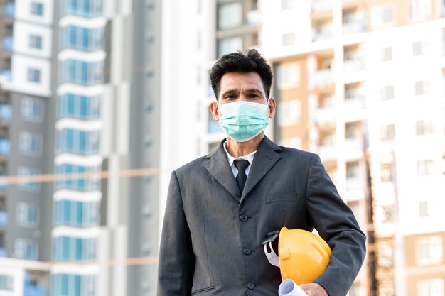 Engenheiro em pé para inspecionar os planos de construção no canteiro de obras