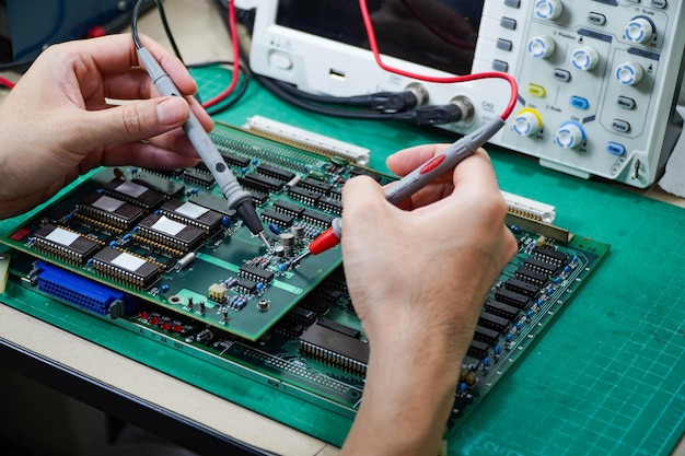 Engenheiro está examinando uma placa de circuito com um osciloscópio de armazenamento digital