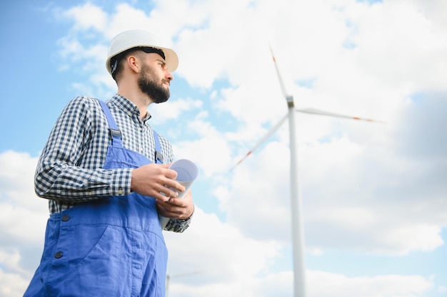 Engenheiro está verificando a produção de energia em turbinas eólicas Trabalhador no parque de moinhos de vento