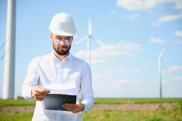 Engenheiro está verificando a produção de energia em turbinas eólicas Trabalhador no parque de moinhos de vento