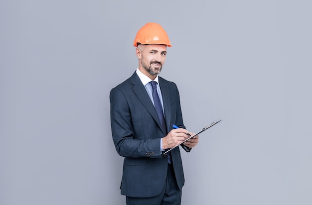 Engenheiro homem de terno e capacete de segurança fazendo anotações assinando contrato