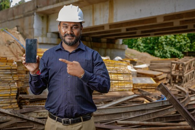 Engenheiro indiano segurando celular enviar mensagem tecnologia de internet Engenheiro de inspeção de construção projeto de construção