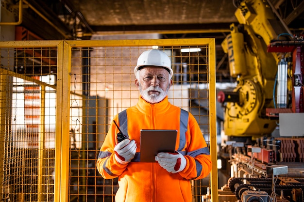 Engenheiro industrial com computador em pé pela máquina automatizada e verificando o processo de produção.