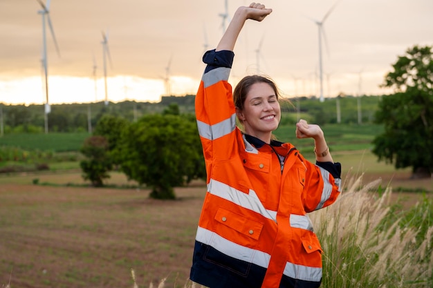 Foto engenheiro inteligente com capacete de proteção levantando as mãos no campo de turbinas elétricas