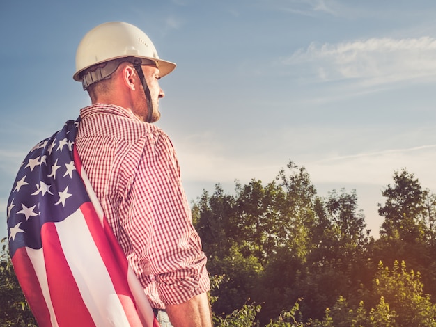 Engenheiro jovem, capacete de segurança branco e bandeira americana