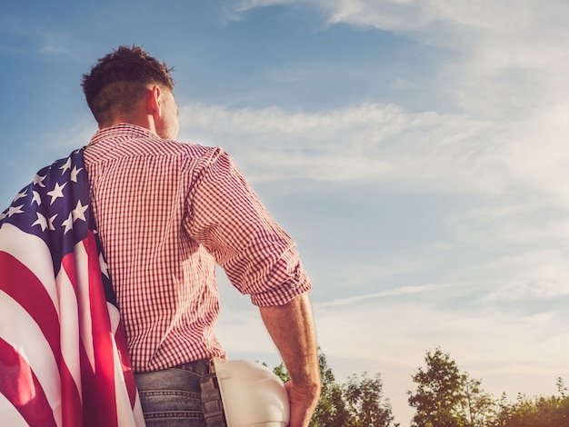 Engenheiro jovem, capacete de segurança branco e bandeira americana