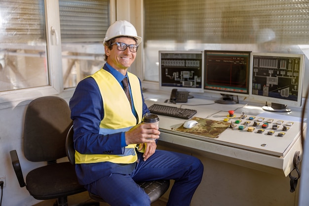 Foto engenheiro masculino alegre com uma xícara de café trabalhando na fábrica