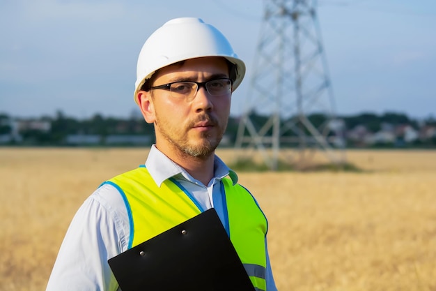 Engenheiro masculino em um capacete e óculos usa um smartphone para trabalho de campo perto de um reboque de telecomunicações