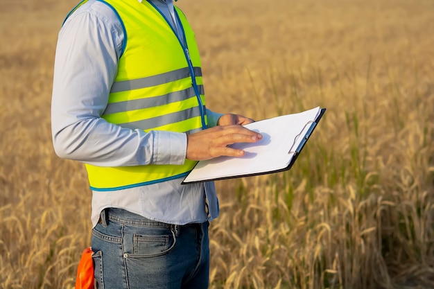 Engenheiro masculino em um capacete e óculos usa um smartphone para trabalho de campo perto de um reboque de telecomunicações