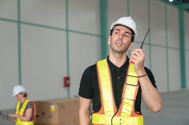 Engenheiro masculino usando capacete de segurança vestindo colete reflexivo usando ferramentas de comunicação Walkie Talkie