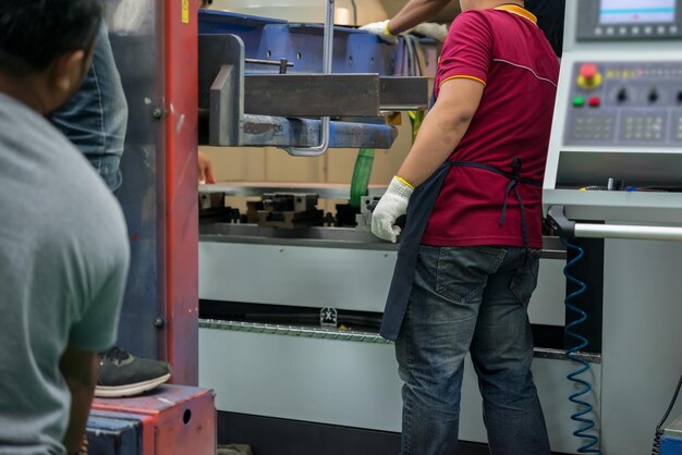 Foto engenheiro mecânico trabalhando na fábrica de máquinas-ferramentasasian torno technician at workpessoas da tailândiatrabalhador industrial bonito asiático operando máquina cnc