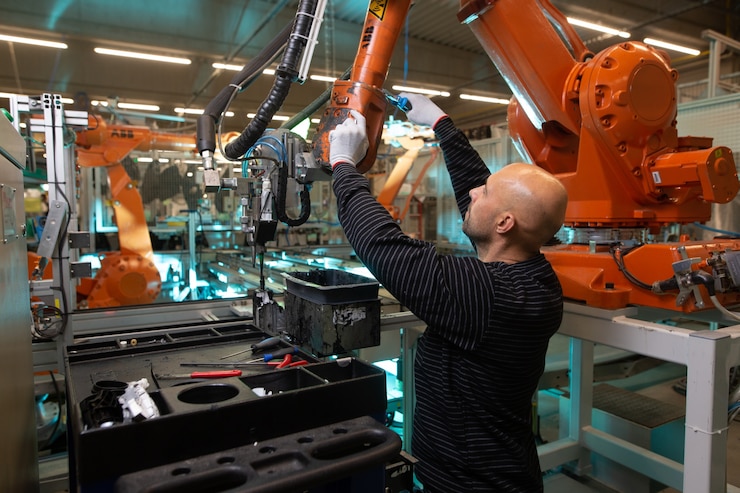 Foto engenheiro otimizando a produção por braço robótico em fábrica inteligente automotiva, funcionário na indústria, conceito industrial