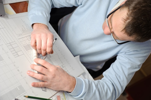 Engenheiro ou arquiteto de blusa azul está trabalhando nos planos de construção.