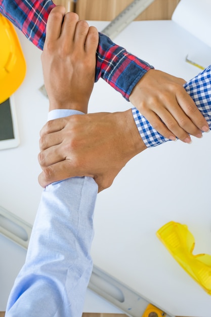 Foto engenheiro ou arquiteto e empresário unidos mãos juntos para o trabalho em equipe.