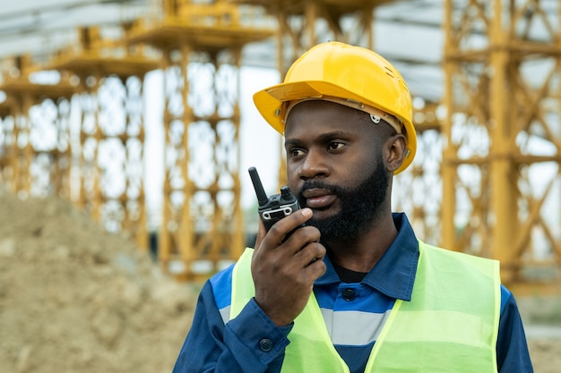 Engenheiro ou capataz de etnia africana usando walkie-talkie